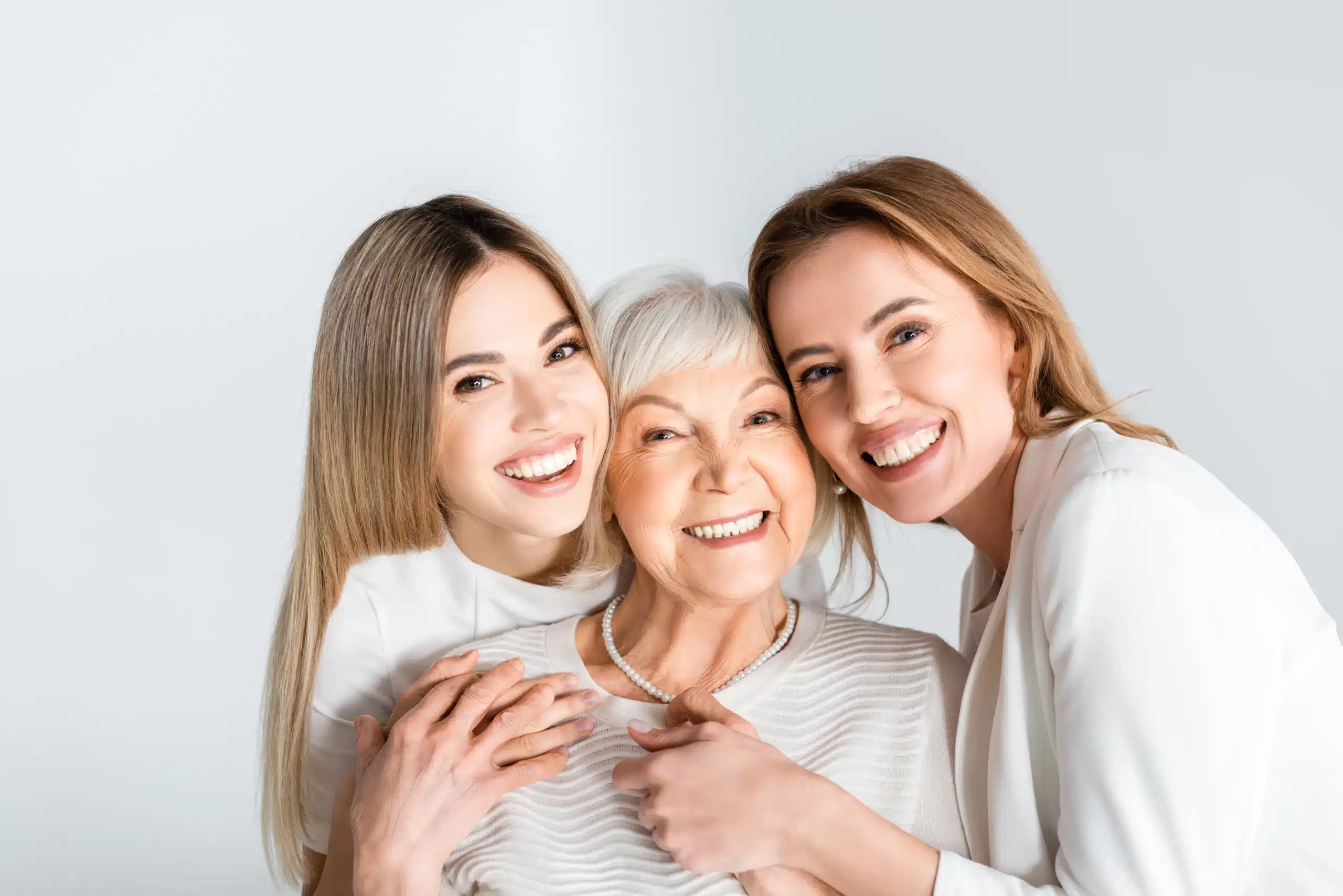 Three smiling women from different generations embracing and showing healthy teeth after Restorative Dentistry at Gridley Dental