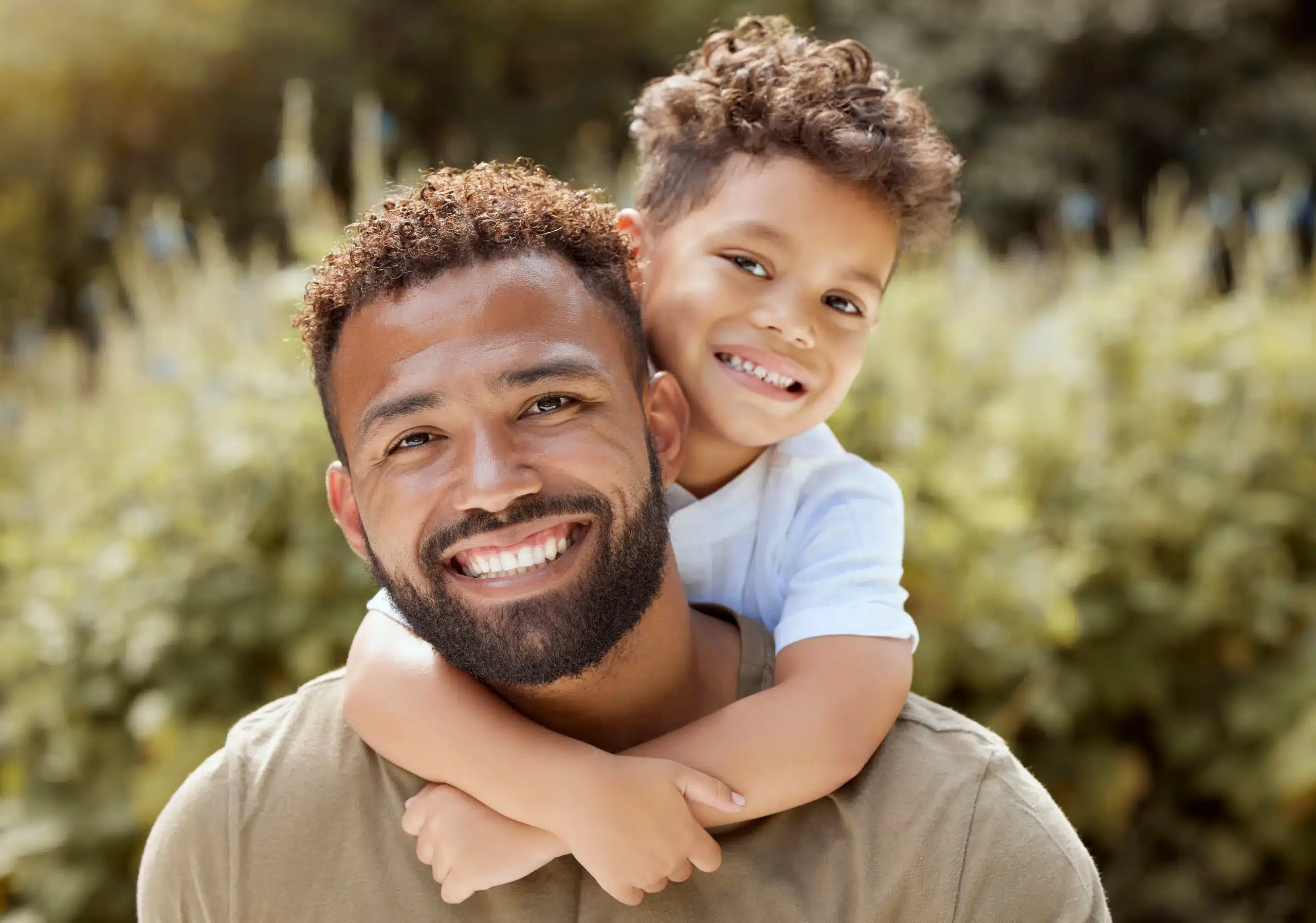 Smiling father and son outdoors showing bright, healthy teeth after Cleanings & Exams at Gridley Dental.