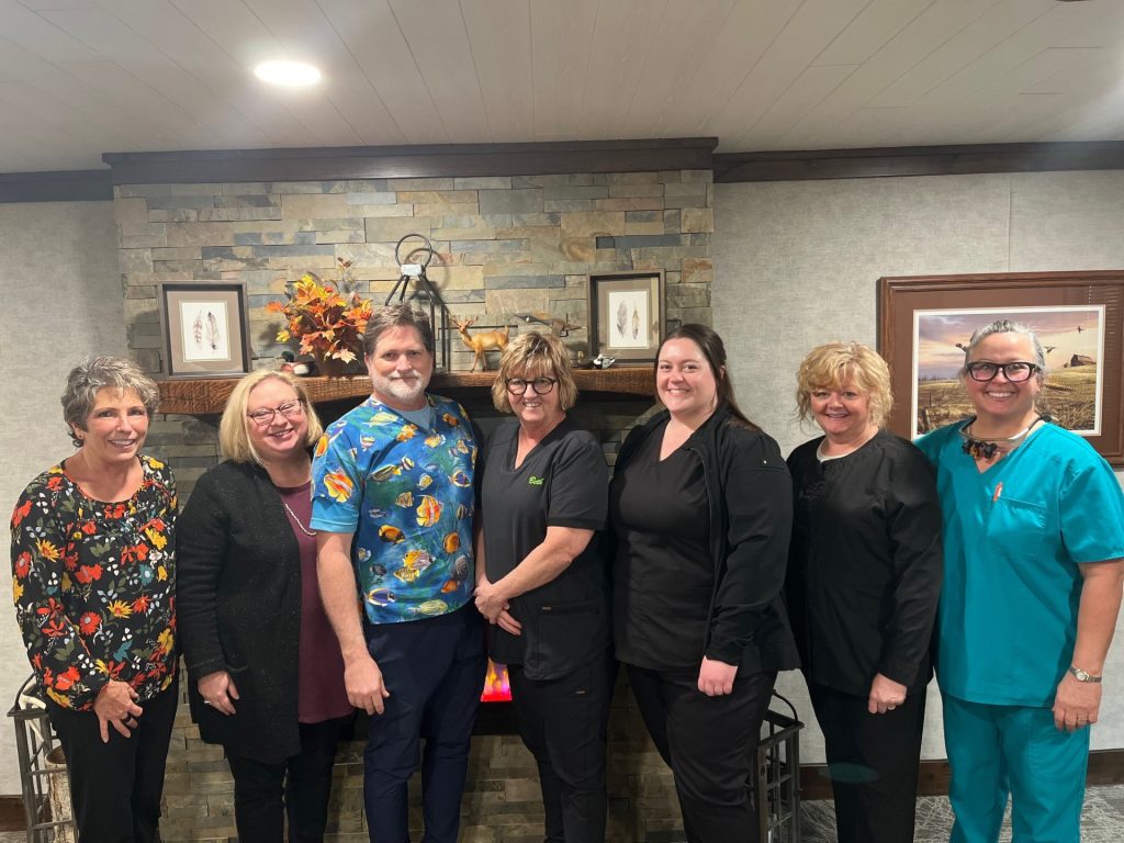 Dr. Timothy Supan with the Gridley Dental team in front of the office's stone fireplace